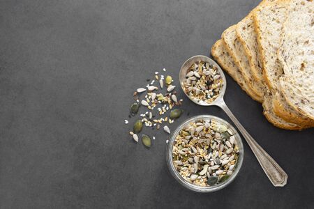 Healthy bread slices on dark background with mix of seeds, top view.