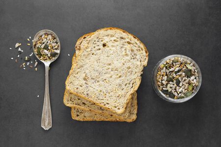 Healthy bread slices on dark background with mix of seeds, top view.