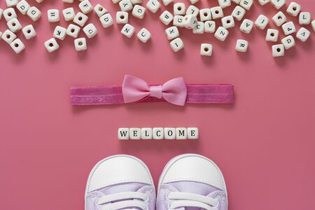 Baby girl pink background with newborn shoes, bow and Welcome words. Baby flat lay, copy space.の写真素材