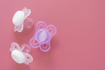 Baby girl pacifier, dummy over pink background. Newborn girl baby abstract flat lay background, copy space.の写真素材