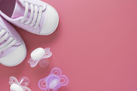 Baby girl background. Newborn shoes with pacifiers, pink background with copy space for text.の写真素材