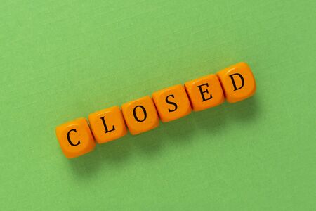 Closed inscription made from orange cubes over green background.の写真素材
