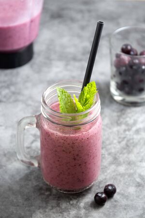 Fresh fruit berry smoothie, glass jar with mint leaves, grey background. Detox, summer drink.の写真素材
