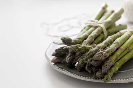 Fresh asparagus, grey plate over white backgroundの写真素材