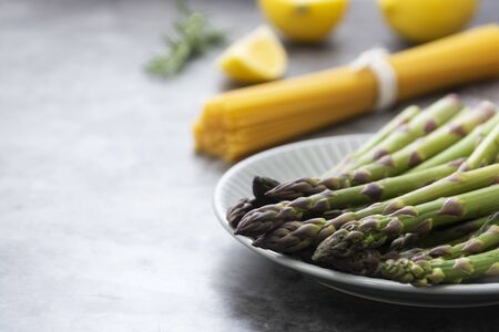 Raw pasta and asparagus on a dark background, cooking healthy foodsの写真素材