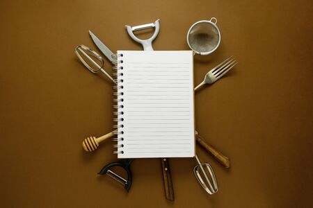 Cooking concept. Kitchen tools and empty note book. Brown background.の写真素材