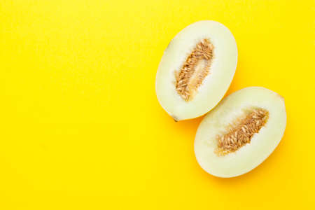 Cut ripe melon isolated on yellow background. Copy space for text.の写真素材