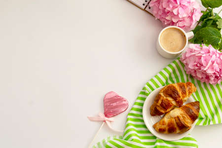 Breakfast with croissants, pink rose flower, petals, vintage plates and black coffee composition....