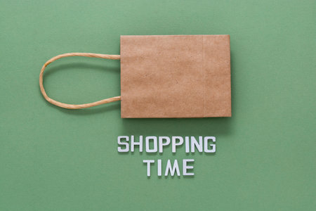 Shopping time word with craft brown paper shopping bag isolated on green background.の写真素材