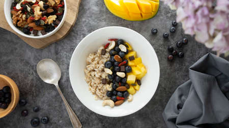 Oatmeal with dried fruits, nuts and mango. Healthy breakfast, dieting and nutrition.