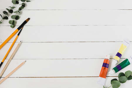 Paints and brushes. Abstract artistic diy background with copy space. White wooden background.の写真素材