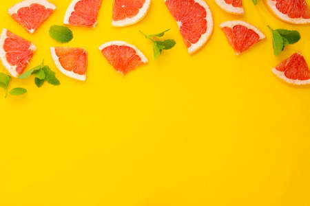 Grapefruit slices on yellow background. Abstract fruit frame mock up.の写真素材