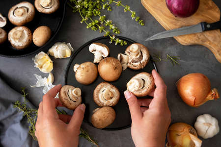 Cooking healthy food. Hands holding champignon mushrooms, top view.