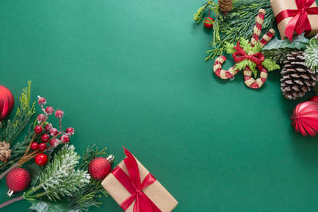 Christmas green background with winter decorations, gift boxes, fir branches, pine cones and red...