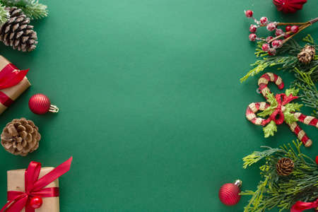 Christmas green background with winter decorations, gift boxes, fir branches, pine cones and red...