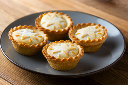 Mince pies with raisins and cinnamon on wooden background