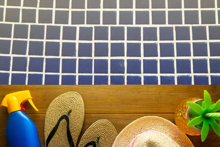 Summer accessories on wood plank with blue water swimming pool. Summer holidays concept.