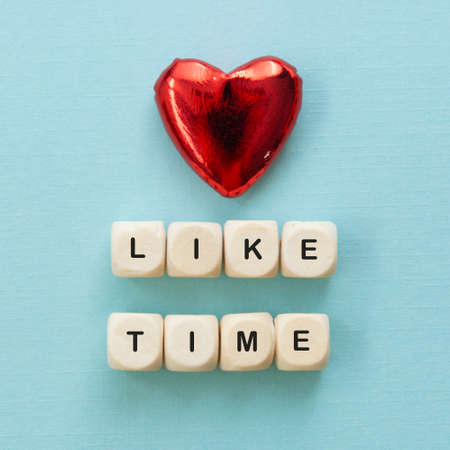 Like time words, made of wooden letters with red heart on blue background. Social media concept.