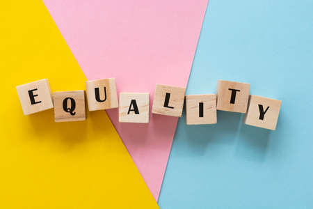 Equality word made withwooden blocks over colorful pink, yellow, blue background, inclusion conceptの写真素材