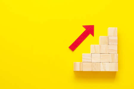 Business growth concept abstract yellow background. Red arrow and wooden stairs.