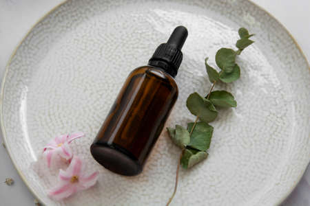 Essence serum. Dark pipette botle, cosmetics skin care. Dried plants pink flowersの写真素材