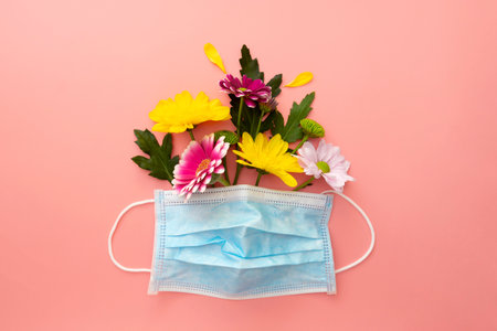 Medical blue face protective mask with colorful flowers. Creative concept of seasonal allergies. Spring 2021 concept.の写真素材