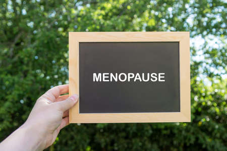 Menopause word abstract text written on chalck board, green blurred backgroundの写真素材