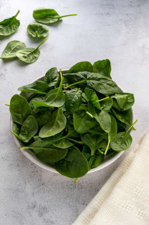 Fresh spinach leaves in a bowl on gray background. Healthy food ingredientsの写真素材