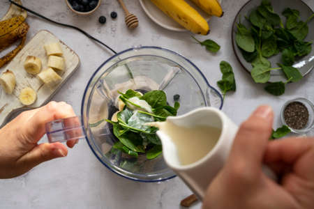 Cooking, preparring green spinach, banana and blueberry smoothie. Female hands, top view. Step by step photos.の写真素材