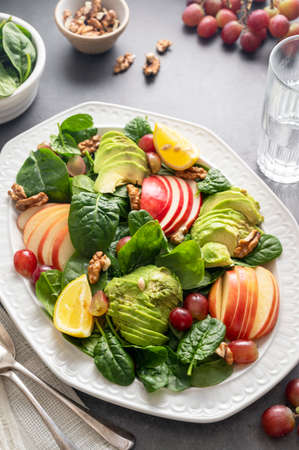 Healthy salad with red apple, wallnuts, grapes and fresh spinach leaves, top viewの写真素材