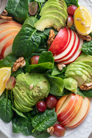 Healthy salad closeup made with red apple, wallnuts, grapes and fresh spinach leaves, top viewの写真素材