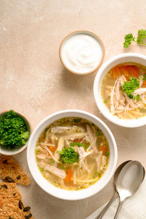 Chicken noodle soup, two bowls with vegetable broth top viewの写真素材