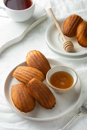 Madeleine cakes, french pastry. Served with cup of tea and honey. Breakfast on table.の写真素材