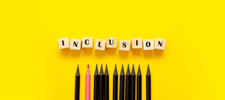 Inclusion concept banner on wooden cubes and pencils yellow backgroundの写真素材