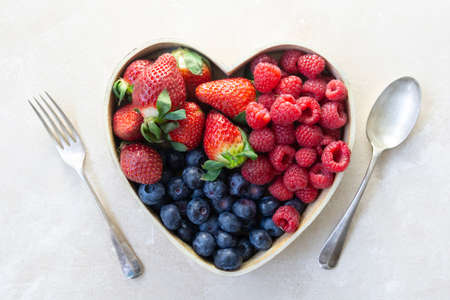 Assortment berries blueberries, strawberries and raspberries in heart wooden box. Healthy food.の写真素材