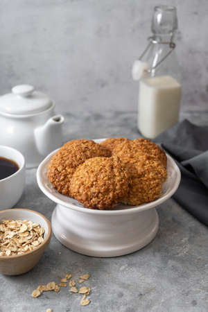 Delicious homemade oat cookies with a cup of coffee, healthy sweet snack bright background.