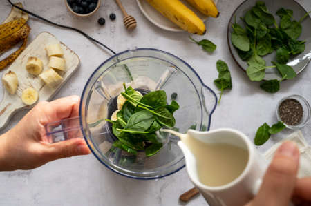 Cooking, preparring green spinach, banana and blueberry smoothie. Female hands, top view. Step by step photos.の写真素材