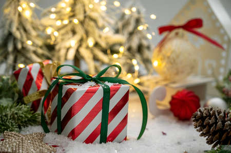 Christmas striped gift box with green ribbon bow, light bokeh, winter decorations, greeting cards
