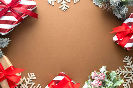 Christmas gift boxes wrapped in craft paper with red bow and winter decorations on brown background....
