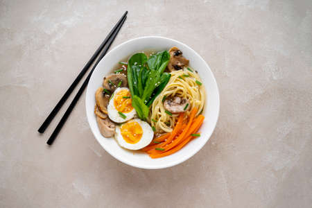Asian vegan soup with noodles, vegetable broth, mushrooms, eggs, carrots and choi sum leavesの写真素材