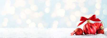 Christmas abstract banner with red baubles decoration, on blue background with snow, copy space for textの写真素材