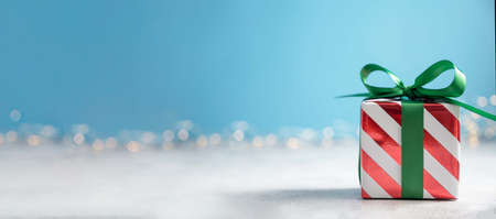 Christmas banner red gift box with green ribbon on blue background with bokeh lights. Copy space for textの写真素材