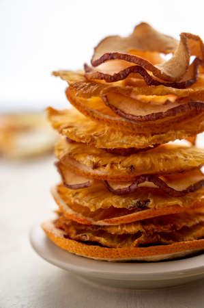 Close up dried fruits stack, pineapple and apples slices on bright background. Vegan, healthy snack, dessertの写真素材