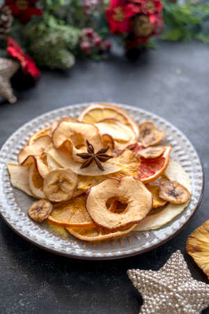Delicious dried fruit slices of orange, banana, mango, grapefruit, pineapple in a plate.