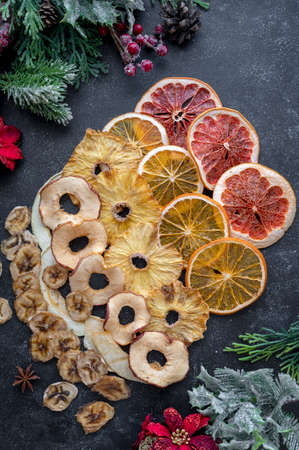 Homemade dried fruit slices of orange, apple, banana, mango, grapefruit, pineapple on a dark backgroundの写真素材