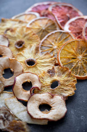 Homemade dried fruit slices of orange, apple, banana, mango, grapefruit, pineapple on a dark backgroundsの写真素材