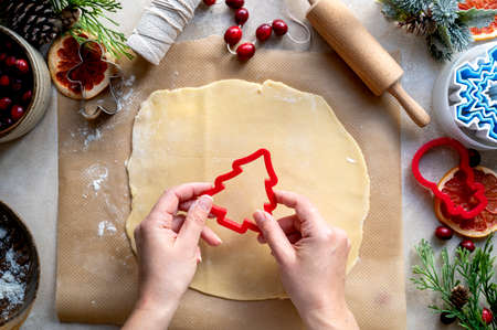 Cooking Christmas cookies. Female hands with christmas tree cookie cutter. Step by step recipe. Top view.の写真素材