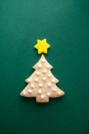Christmas tree cookie with icing and star on green background, top viewの写真素材