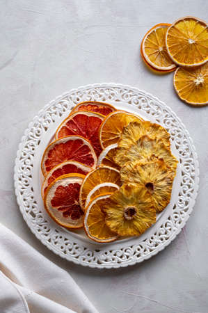 Homemade dried fruit slices of orange, grapefruit, pineapple in a plate. Healthy snack, dessertの写真素材