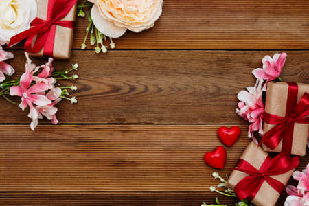 Festive gift boxes and bouquet of flowers on wooden background with copy space. Valentine's dayの写真素材